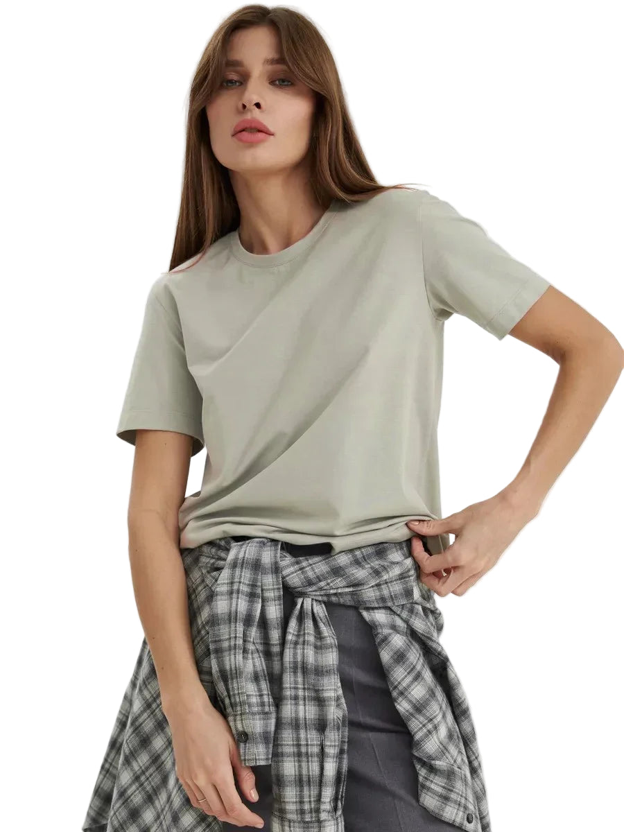 Woman wearing a light green t-shirt and plaid skirt on a white background