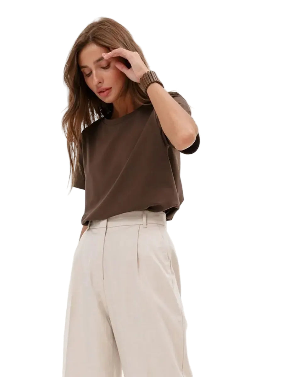 Woman wearing a brown top and beige pants on a white background