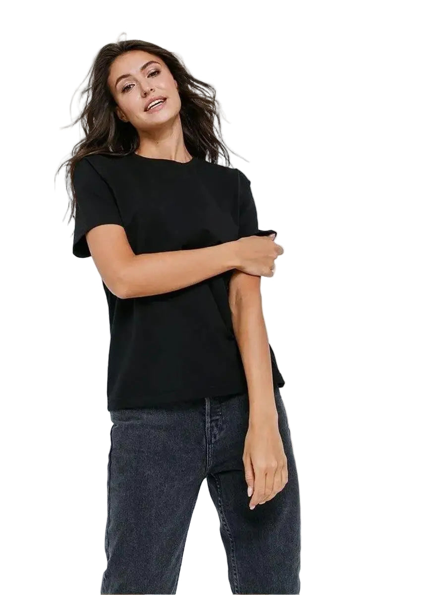 Woman wearing a black t-shirt and dark jeans on a white background