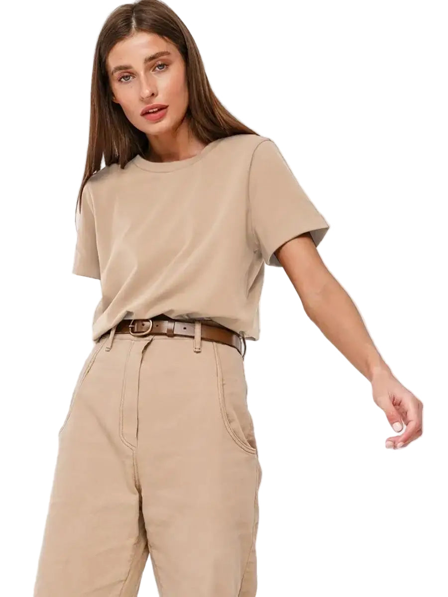 Woman wearing a beige t-shirt and pants with a belt on a white background